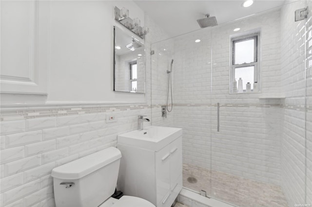 bathroom featuring vanity, toilet, a shower with shower door, and tile walls