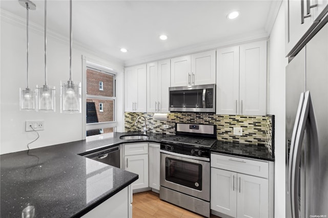 kitchen featuring ornamental molding, stainless steel appliances, sink, pendant lighting, and white cabinets