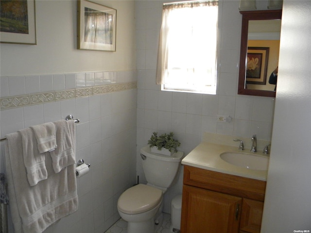 bathroom with vanity, toilet, and tile walls