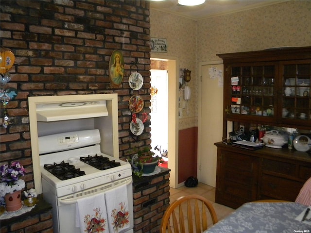 kitchen featuring crown molding, light tile patterned floors, and white gas range oven