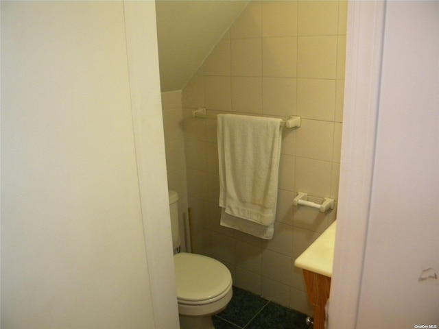 bathroom with tile patterned flooring, vanity, toilet, and tile walls