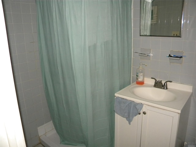 bathroom with a shower with shower curtain, vanity, and tile walls