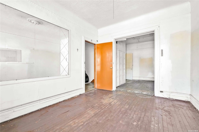 unfurnished bedroom with a textured ceiling, a closet, and dark hardwood / wood-style floors