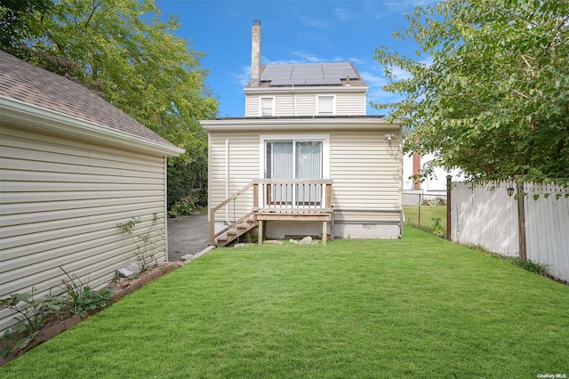 back of property featuring a lawn and solar panels