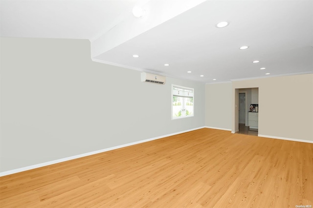 spare room featuring a wall unit AC, crown molding, and light hardwood / wood-style floors