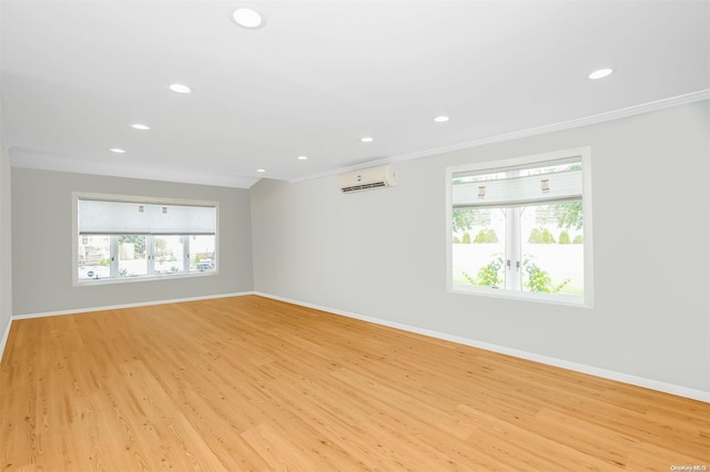 empty room featuring a wall mounted air conditioner, crown molding, and light hardwood / wood-style flooring