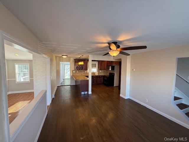 unfurnished living room with ceiling fan and dark wood-type flooring