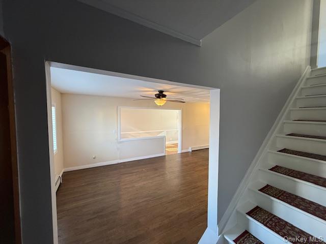 stairs with ceiling fan, wood-type flooring, and a baseboard heating unit