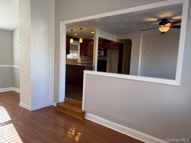 interior space featuring ceiling fan, hanging light fixtures, and dark wood-type flooring