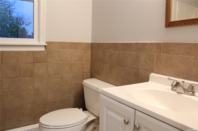 bathroom with vanity, toilet, and tile walls