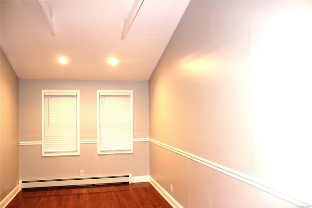 empty room featuring dark wood-type flooring and a baseboard heating unit