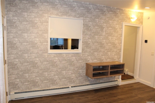 interior space featuring dark wood-type flooring, a baseboard radiator, and brick wall