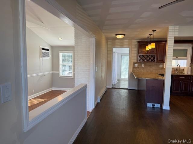 corridor with sink, a baseboard radiator, dark hardwood / wood-style floors, an AC wall unit, and lofted ceiling