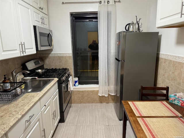 kitchen with light tile patterned flooring, light stone counters, white cabinets, and stainless steel appliances