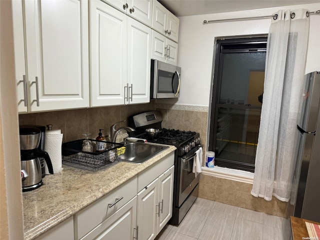 kitchen with sink, white cabinetry, stainless steel appliances, and light tile patterned floors