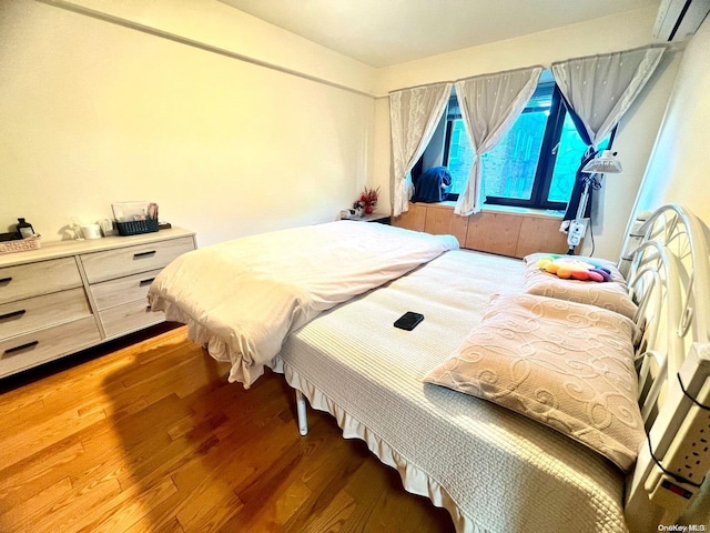 bedroom with a wall mounted AC and hardwood / wood-style floors