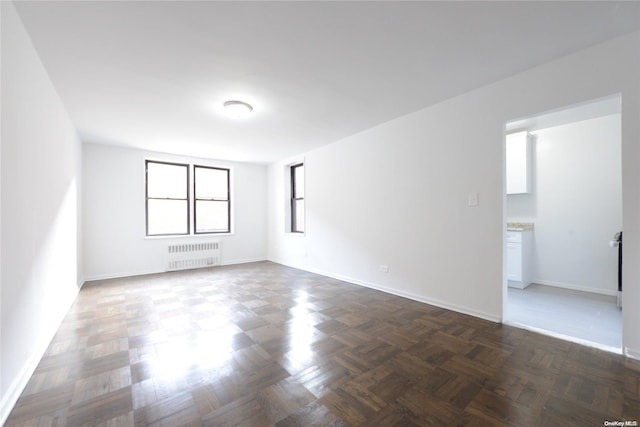 spare room featuring dark parquet flooring and radiator heating unit