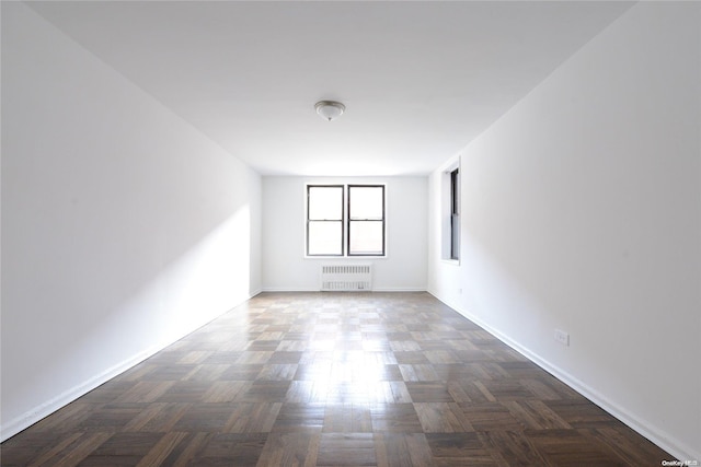 empty room featuring dark parquet flooring and radiator