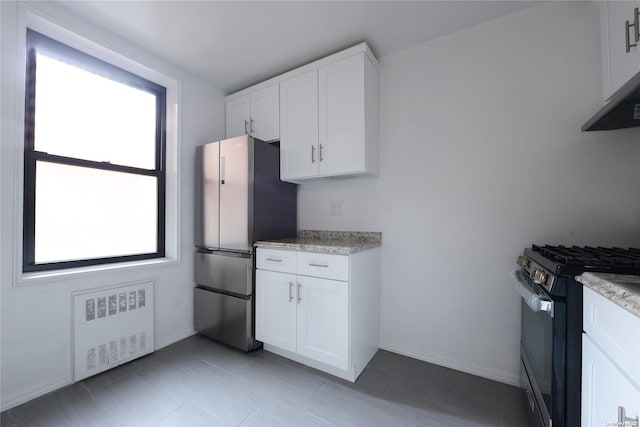 kitchen featuring white cabinets, a wealth of natural light, stainless steel appliances, and radiator