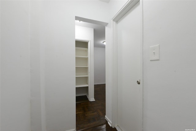 walk in closet with dark parquet flooring