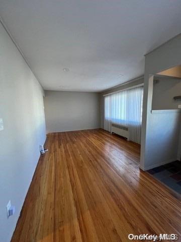 empty room with radiator heating unit and hardwood / wood-style floors