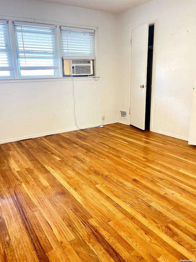 unfurnished room with cooling unit and light wood-type flooring