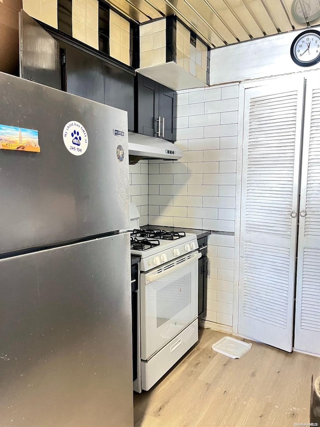 kitchen featuring tasteful backsplash, stainless steel fridge, light hardwood / wood-style floors, and white range with gas cooktop