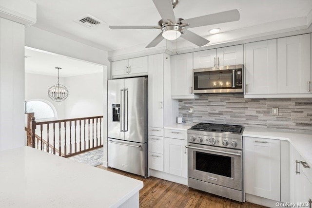 kitchen featuring hanging light fixtures, dark hardwood / wood-style flooring, high quality appliances, white cabinets, and ceiling fan with notable chandelier