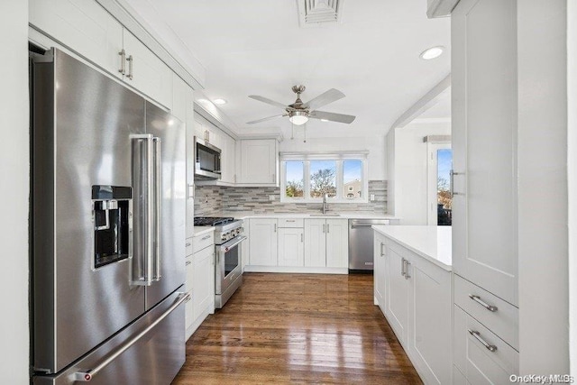 kitchen with sink, dark hardwood / wood-style flooring, decorative backsplash, white cabinets, and high end appliances