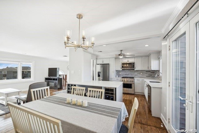 dining room with ceiling fan with notable chandelier, dark hardwood / wood-style flooring, ornamental molding, and sink