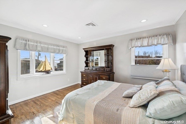 bedroom featuring hardwood / wood-style floors, crown molding, and multiple windows