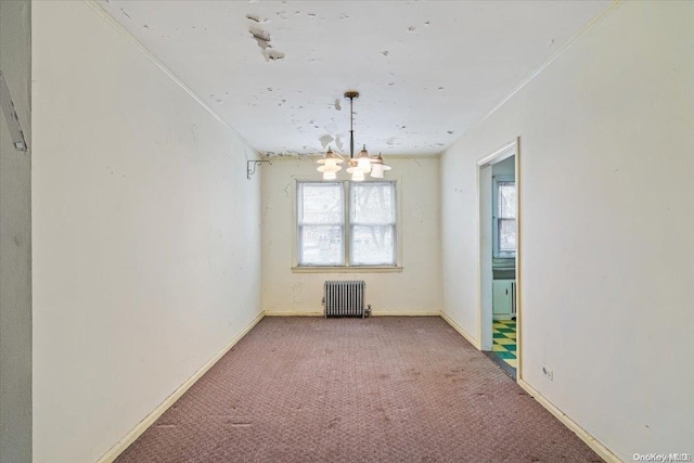 carpeted empty room with radiator, ornamental molding, and an inviting chandelier