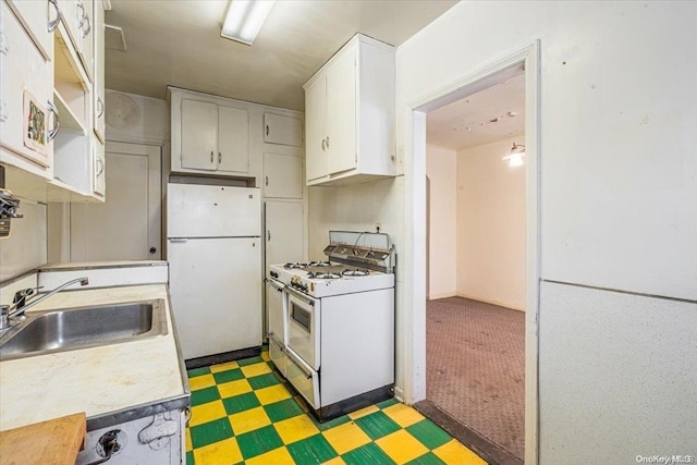 kitchen with sink, white cabinets, dark carpet, and white appliances