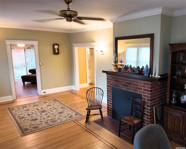 living room with wood-type flooring, a brick fireplace, ceiling fan, and crown molding