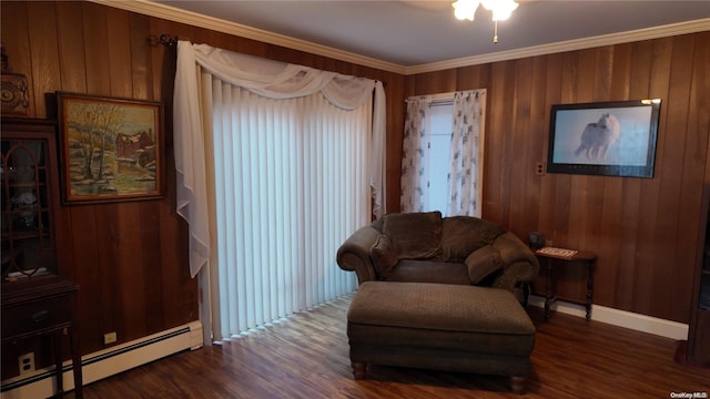 sitting room featuring wood walls, dark hardwood / wood-style flooring, ornamental molding, and a baseboard heating unit