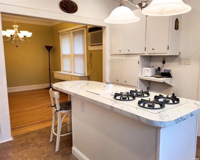 kitchen with dark wood-type flooring, crown molding, a notable chandelier, white cabinets, and hanging light fixtures