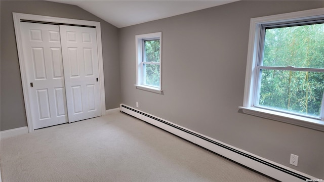 unfurnished bedroom with multiple windows, a closet, baseboard heating, and lofted ceiling