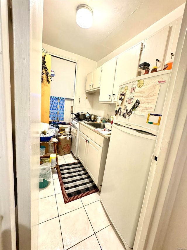 kitchen with white cabinetry, light tile patterned flooring, and white appliances