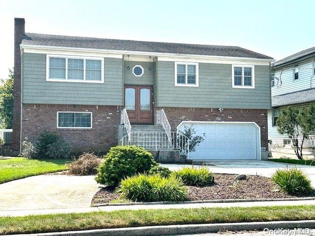 1070 Mckinley St, Baldwin, NY 11510 - raised ranch with an attached garage, driveway, brick siding, french doors, and entry steps