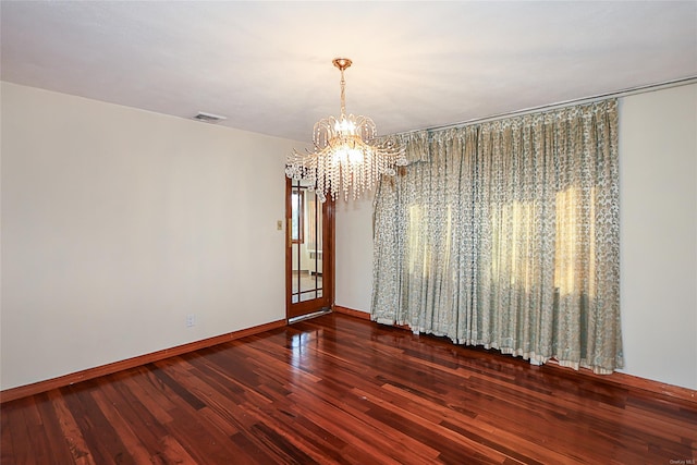 empty room featuring dark hardwood / wood-style floors and an inviting chandelier