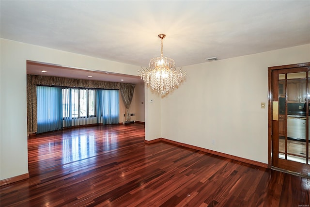 empty room with a notable chandelier and dark hardwood / wood-style floors