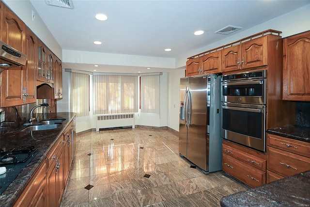 kitchen featuring radiator, stainless steel appliances, extractor fan, sink, and dark stone countertops