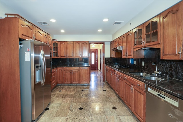 kitchen with decorative backsplash, appliances with stainless steel finishes, dark stone countertops, and sink