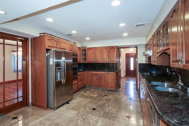 kitchen with dark stone countertops, decorative backsplash, sink, and appliances with stainless steel finishes