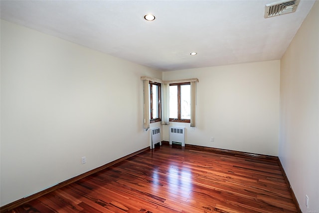 empty room featuring radiator heating unit and dark hardwood / wood-style floors