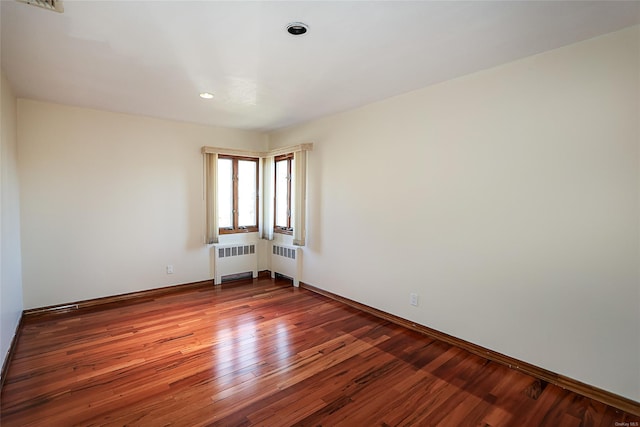 empty room with hardwood / wood-style floors and radiator heating unit