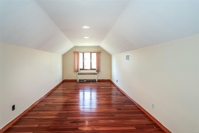 bonus room with dark hardwood / wood-style floors, lofted ceiling, and radiator