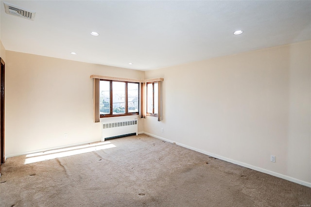 empty room featuring radiator heating unit and light colored carpet