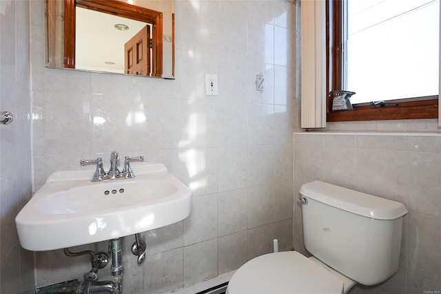 bathroom with sink, toilet, and tile walls