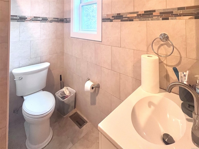 bathroom featuring vanity, toilet, and tile walls